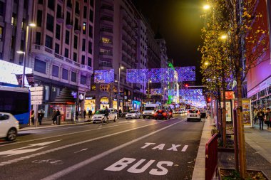 Madrid, İspanya; 12 / 17 / 2019; İspanya 'nın Madrid kentindeki ünlü Gran Via caddesinde trafik ve otobüs şeridi bulunan Noel ışıkları