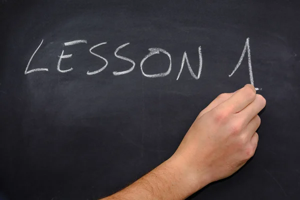 Teacher writing on the blackboard with chalk lesson