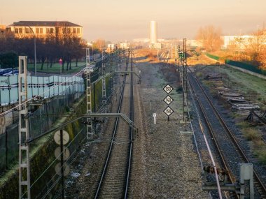 Gölgede Ponferrada şehrinin tren rayları, şafak vakti aydınlatılmış arka plan, N, A ve B tipi trenler için maksimum hız işaretleri ve bir dönüm noktası.