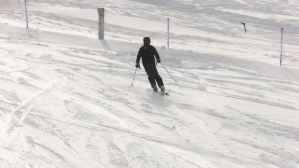 スキー場の雪の山を滑り降りる服と黒いヘルメットのスキー — ストック動画