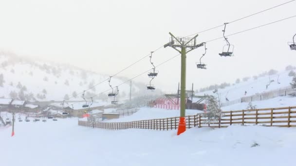 スキー場の雪の斜面にスキー場を降り 雪と霧の中を背景にスキーリフトを降ります — ストック動画
