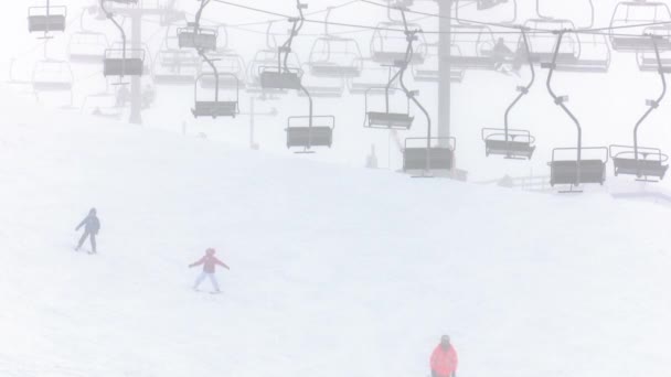 雪が降っている間は子供と大人のスキーやスノーボード クロスカントリースキーリゾートのスキーリフト — ストック動画