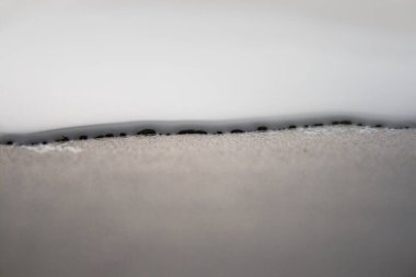 Küçük bir su birikintisinin makro görüntüsü metal zemindeki yüzey geriliminden dolayı statik bir dalga yaratıyor.