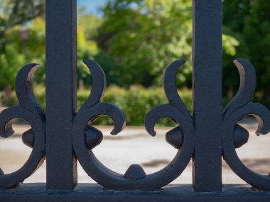 Ağaçlarla dolu bir parkın giriş kapısının demir parmaklıklarının ayrıntıları.