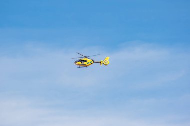 San Sebastian de los Reyes, Madrid, İspanya; 05 / 02 / 2020: Mavi ayrıntılı sarı EC-MZR helikopteri ve bulutlu mavi bir gökyüzünün üzerinde uçan bir kamera