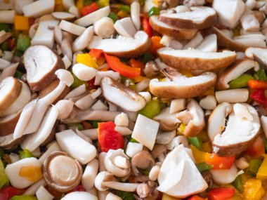 Kızartma tavasında pişen renkli biber parçaları arasında çeşitli mantarlar var.