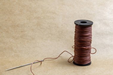 Karton zemin üzerinde iğne olan kahverengi iplik.