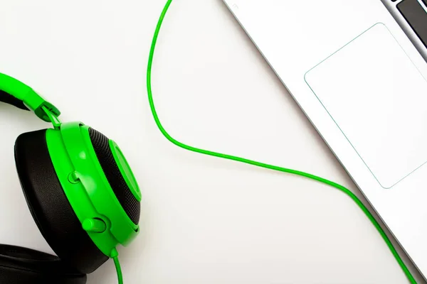 green gaming headphones and steel laptop on a white background