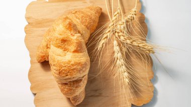 Beyaz arka planda tahtanın üzerinde kuru buğdaylı kruvasanlar.