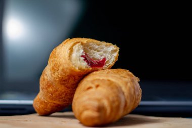 Ay çörekleri çilek reçeli ve kuru buğdayla ısırdı. Tahta bir tahta üzerinde dizüstü bilgisayarın arka planında.