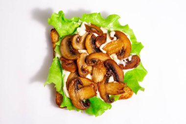 Yeşil yapraklı ekmek tostu kızarmış mantar salatası ve beyaz arka planda beyaz sos.