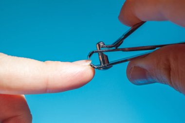 Eldeki metal tırnak makası işaret parmağı mavi arkaplanı kes, kapat, boşluğu kopyala