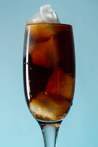 Kahverengi soda ve buz mavisi arkaplanlı cam kadeh, kapat, boşluğu kopyala