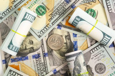 100 dolarlık banknotlar yuvarlanıyor ve beyaz arka planda çeyrek dolar para var.