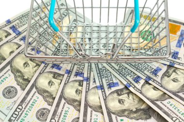 İçine mavi eklenmiş sepet beyaz arka planda yüz dolarlık banknotların üzerinde duruyor. İzole et. Kapat.