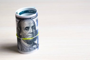 100 dolarlık banknotlar, hafif bir ahşap üzerinde elastik ile bükülmüş ve örülmüş. Yandan bak. Kopyalama alanını kapat