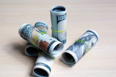 100 dolarlık banknotlar, yumuşak ahşap bir masada elastik rulolarla örülmüş. Yan görünüş. kapatılacak