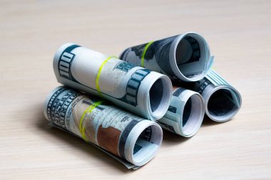 100 dolarlık banknotlar, yumuşak ahşap bir masada elastik rulolarla örülmüş. Yan görünüş. kapatılacak