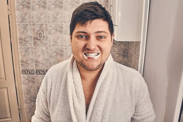 Mężczyzna Białym Płaszczu Stoi Pastą Zębów Ustach Łazience — Zdjęcie stockowe