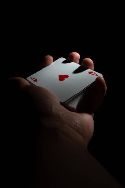 Bir deste iskambil kağıdını elinde tut. Siyah arka plan fotokopi alanında poker kapaklı as. Kapat.