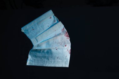 Koyu arkaplan fotokopi alanı üzerinde kan olan mavi tıbbi gazlı bez maskesi. Kapat.