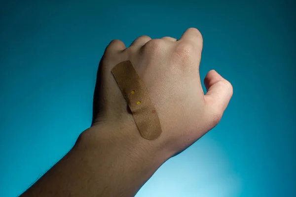 medical plaster on the hand wound, cut on a blue backgroun