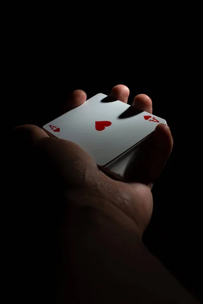 hand hold a deck of cards ace of hearts with poker top on a black background copy space. close up