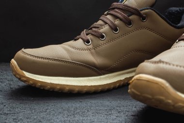 Siyah betonda açık kahverengi deri spor ayakkabılar.