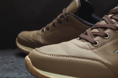 Siyah betonda açık kahverengi deri spor ayakkabılar.