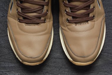 Siyah betonda açık kahverengi deri spor ayakkabılar.