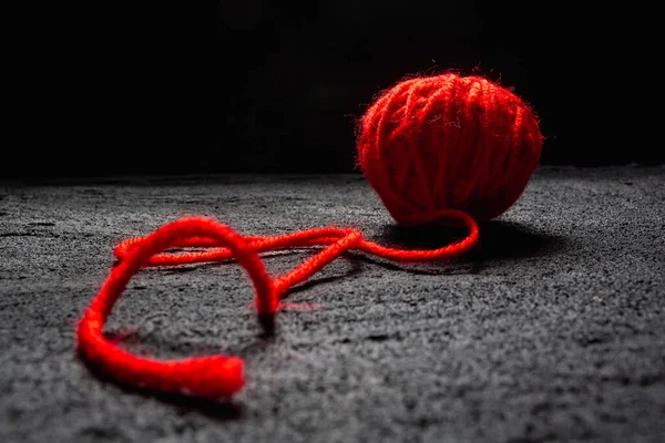 ball of red thread for knitting on black concrete dark background .copy space