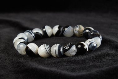 Siyah kadife üzerinde akik bilezik, yarı değerli taş. Kapat.