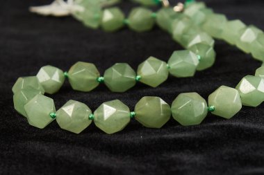 Siyah kadife üzerinde yarı değerli taştan yeşim boncuklar. Kapat.