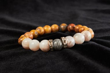 Jasper bileziği siyah kadife üzerinde yarı değerli taş. Kapat.