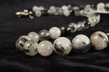 Siyah kadife üzerinde uçucu, yarı değerli bir taşın boncukları. Kapat.