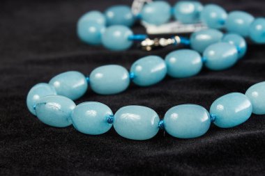 Siyah kadife üzerinde yarı değerli taştan boncuklar. Kapat.