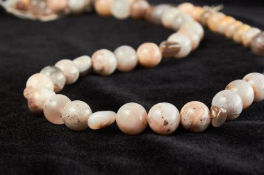 Siyah kadife üzerinde yarı değerli rhodonit taşından boncuklar. Kapat.