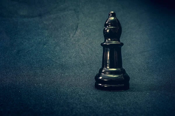 black glass bishop chess piece on dramatic background