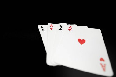 Siyah arkaplanda kart oynayan dört as