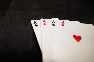 Siyah arkaplanda kart oynayan dört as