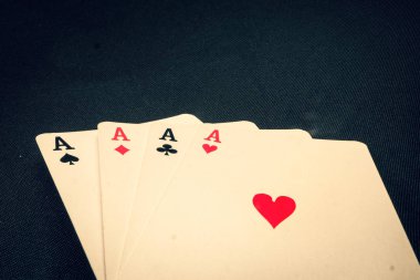 Siyah arkaplanda kart oynayan dört as