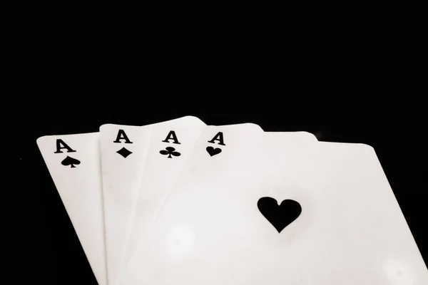 four black aces playing cards on black background