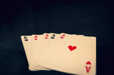 Siyah arkaplanda kart oynayan dört as