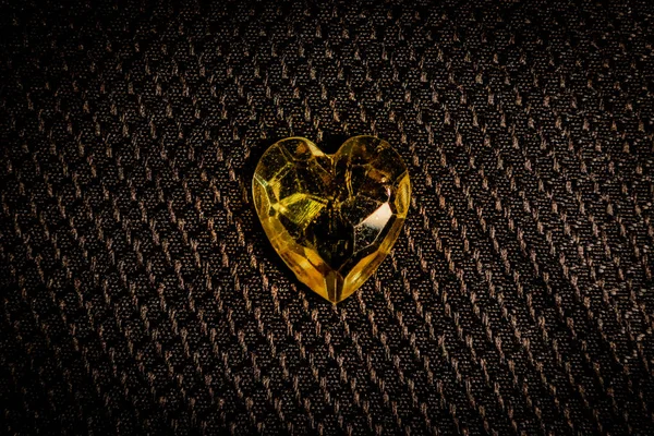 Yellow heart gem stone on black background