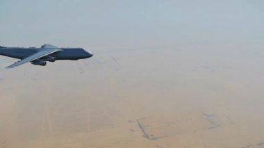 Yan görünümü büyük askeri hava kargo gemisi uçak Ortadoğu ya da Afrika yerde yukarıda gündüz uçan. 4 k'dan fazla işlenen gerçekçi 3d animasyon