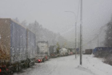 Kış trafiğinde trafik sıkışıklığı olan arabalar. Şehir otobanındaki kış havası, polis arabasının sisli ve kar yolundaki cam pencerelerden geçişi. Kar yağışı, buz, bulanık arkaplan, seç