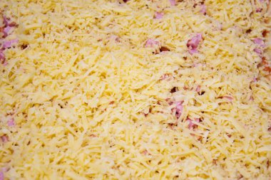 Katman kat hamur mayası, doğranmış sosis ve domates ezmesi, üstü rendelenmiş peynirle kaplı. Ev yapımı pizza pişirme süreci