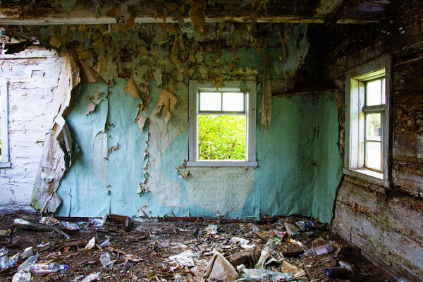 the wall of the collapsed house after the earthquake, a light window against the gray walls. old abandoned house, garbage everywhere.