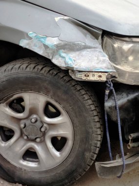 Ön tampon ve kırık arabanın kanadı. Gümüş arabanın önü yolda kaza sonucu hasar gördü. Tampon iple bağlanmış. Araba tamiri ya da sigorta konsepti. Hasarlı Otomatik 'in bulanık görünümü.