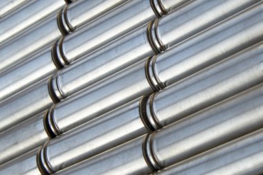 Parlak çelik silindirik yüzeyi olan metal parçalar. Parçalanmış lityum iyon faktör hücresi 2170 pil paketinin açılı görüntüsü. Seçici odaklı soyut sanayi geçmişi.